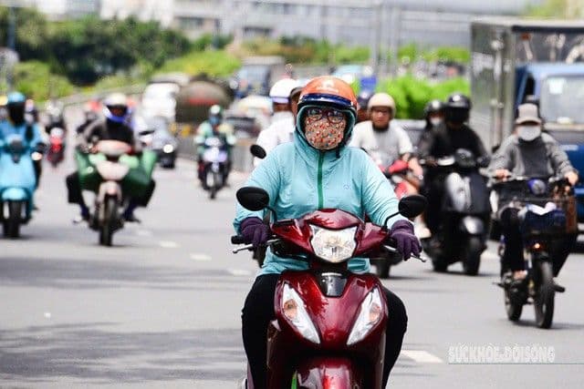 Người dân di chuyển trên đường phố Hà Nội trong nắng nóng gay gắt, che chắn cẩn thận để chống chọi với nhiệt độ cao.