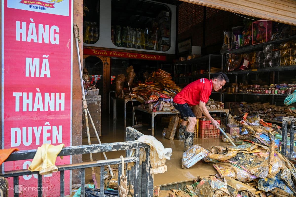 Người dân dọn dẹp bùn đất và tài sản hư hại trong cửa hàng sau khi nước lũ rút.