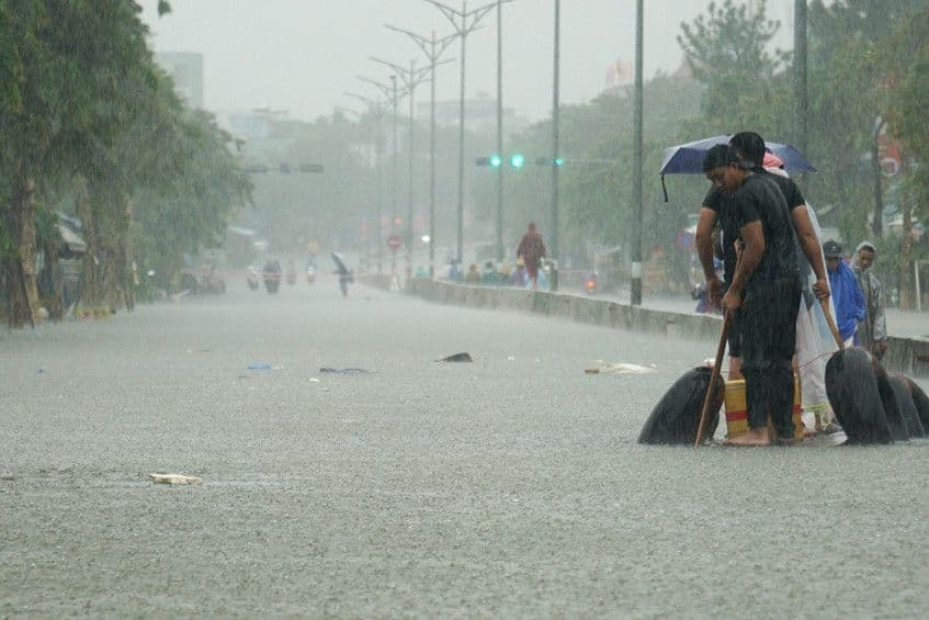 Người dân dọn dẹp đường phố ngập lụt sau mưa lớn, minh họa tác động của thiên tai lên hạ tầng và đời sống.