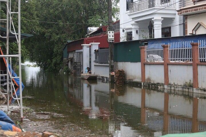 Người dân dùng thuyền di chuyển qua khu vực nhà cửa ngập lụt ở ngoại thành Hà Nội do bão số 4, minh họa sự yếu kém của hạ tầng