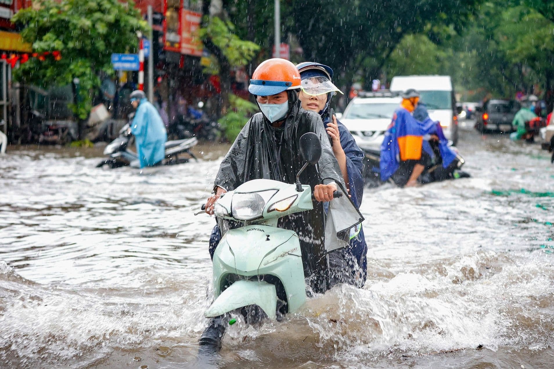 Người dân dắt bộ xe máy qua tuyến phố Hà Nội ngập sâu do mưa lớn.