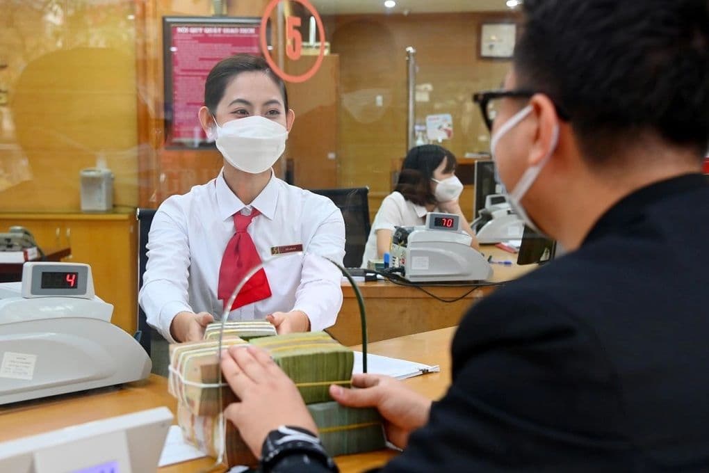 Người dân giao dịch tiền mặt tại ngân hàng, minh họa cho việc chuyển đổi chi trả lương hưu không tiền mặt