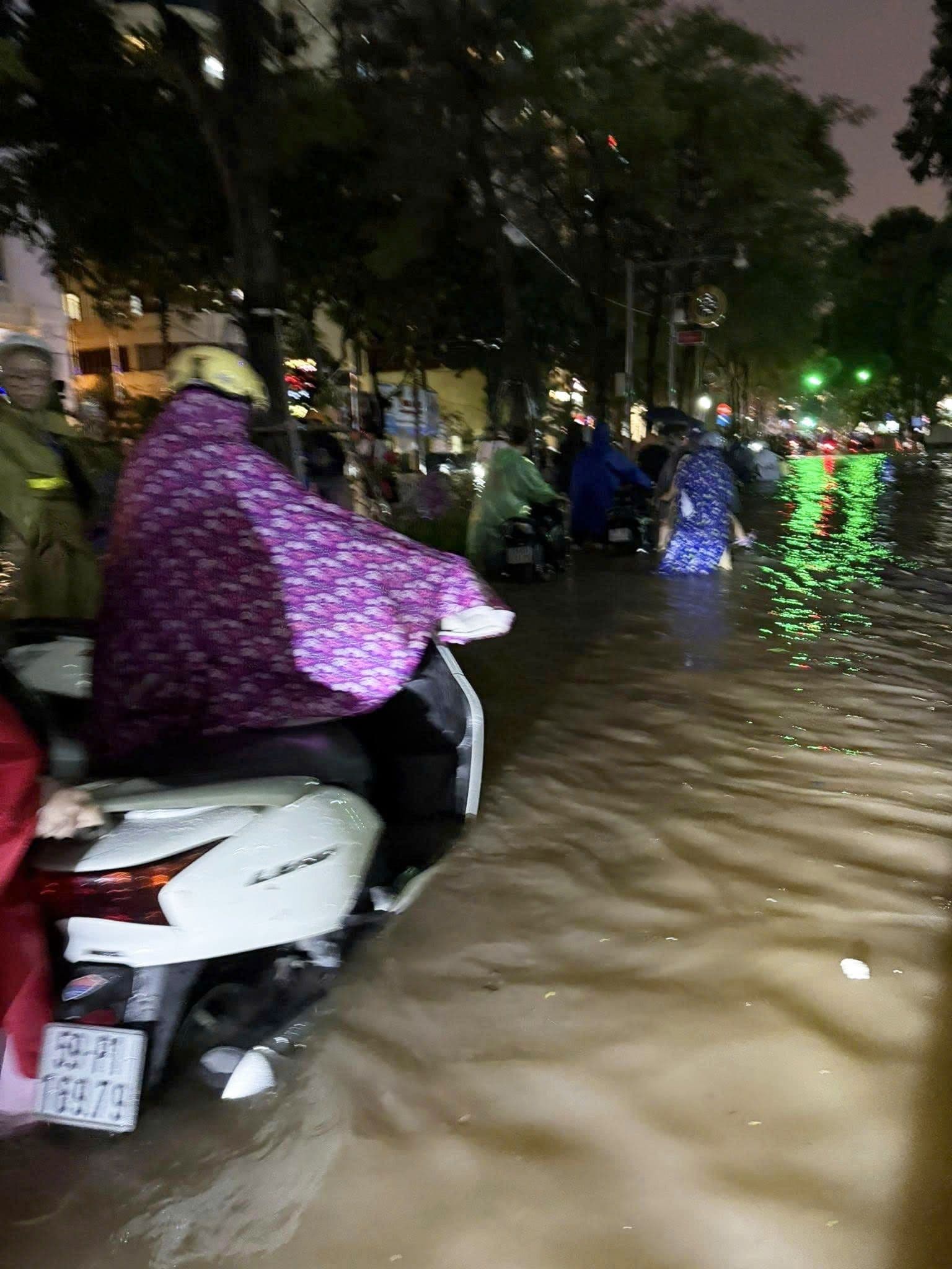 Người dân Hà Nội bì bõm lội nước về nhà trên đường phố ngập lụt vào ban đêm.