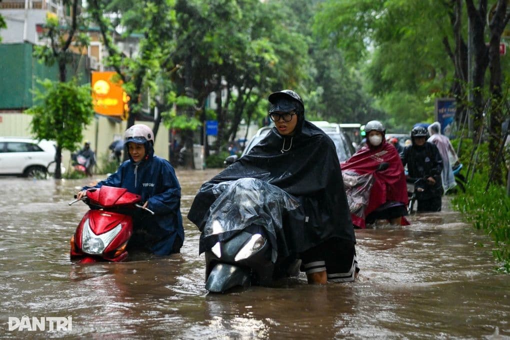 Người dân Hà Nội chật vật di chuyển qua đường phố ngập sâu do mưa lớn, phản ánh thách thức về biến đổi khí hậu.