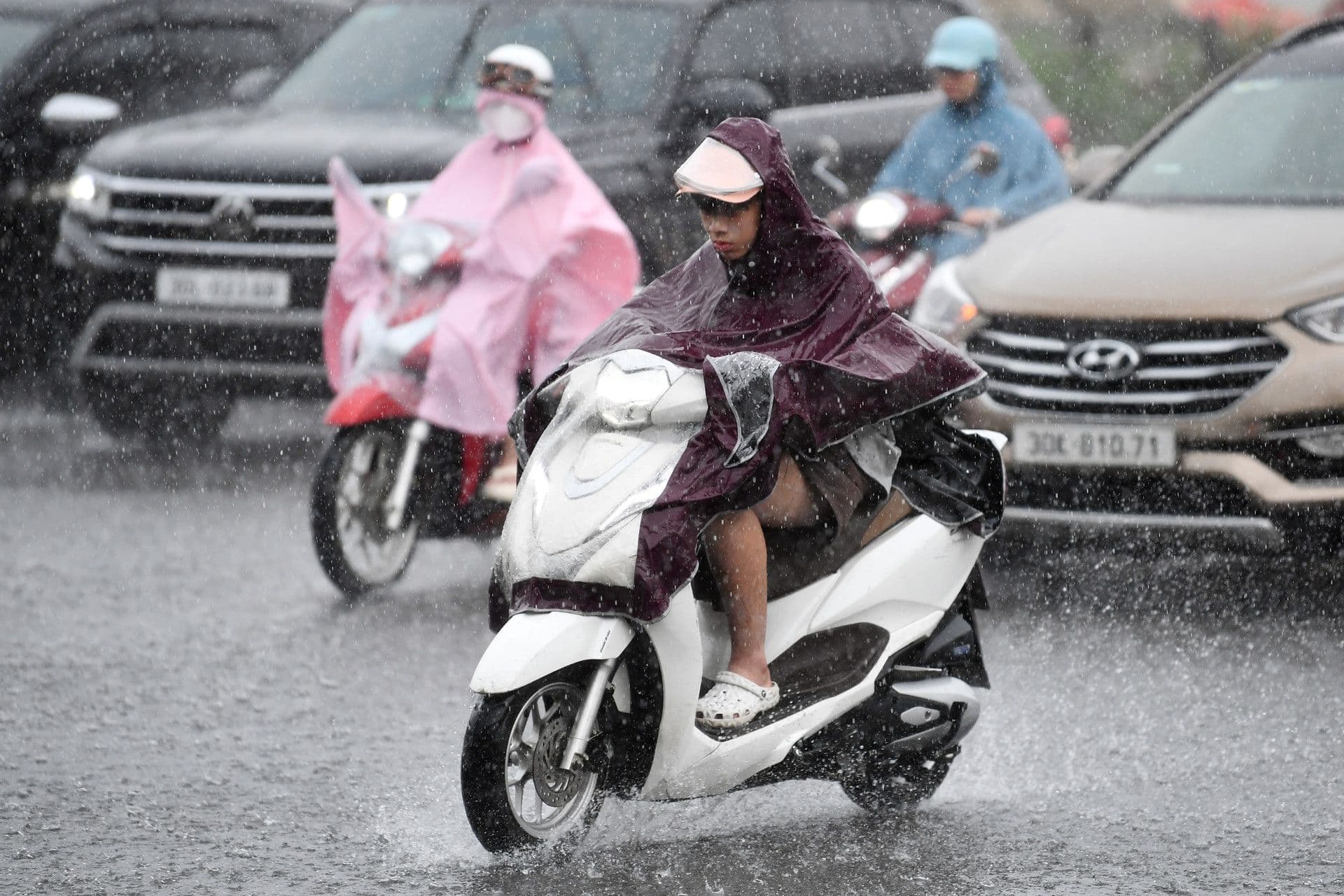 Người dân Hà Nội di chuyển bằng xe máy dưới trời mưa lớn gây khó khăn cho giao thông.
