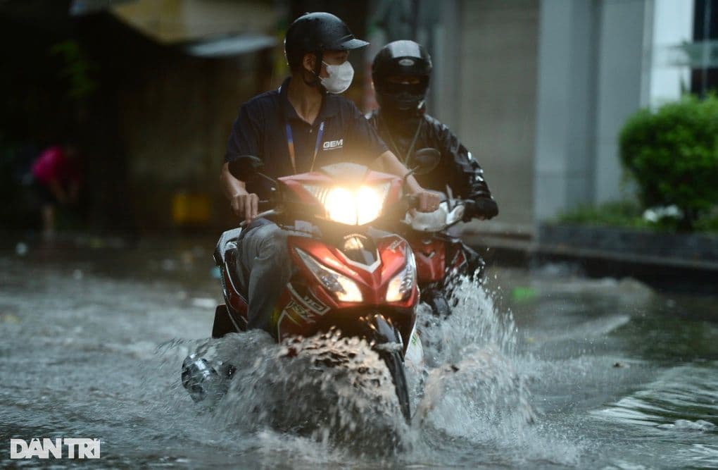 Người dân Hà Nội di chuyển qua đường ngập nước do mưa lớn.