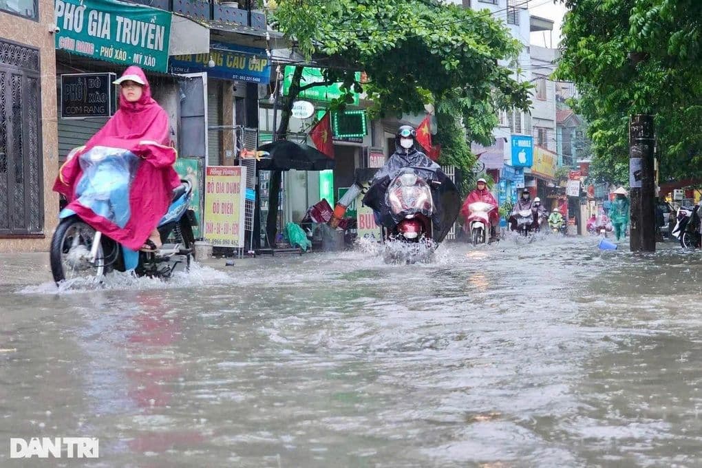 Người dân Hà Nội di chuyển qua đường ngập nước trong mưa lớn