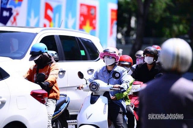 Người dân Hà Nội di chuyển trên đường phố nóng bức, che chắn kỹ lưỡng dưới nắng gắt.