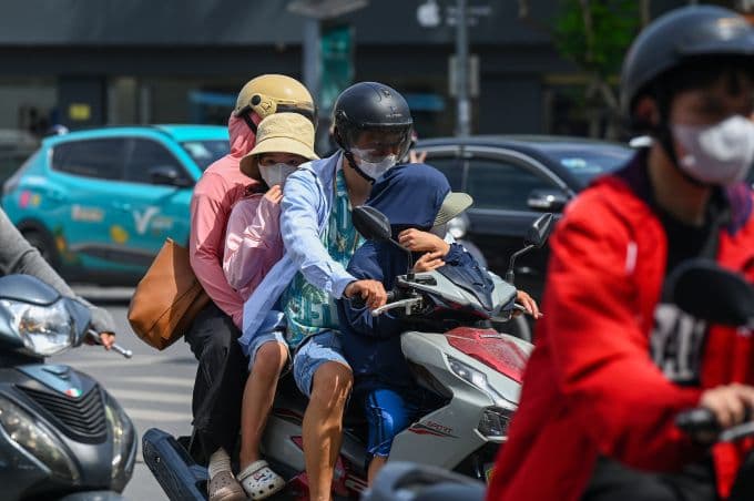 Người dân Hà Nội di chuyển trên đường trong cái nắng gay gắt, mặc đồ chống nắng để bảo vệ cơ thể.