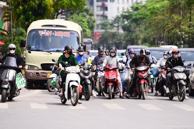 Người dân Hà Nội di chuyển trên đường trong cái nắng gay gắt, nhiều người che chắn để chống nóng.