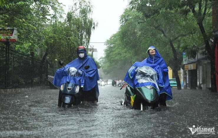 Người dân Hà Nội đi xe máy lội nước trên đường ngập lụt trong cơn mưa lớn do bão số 10