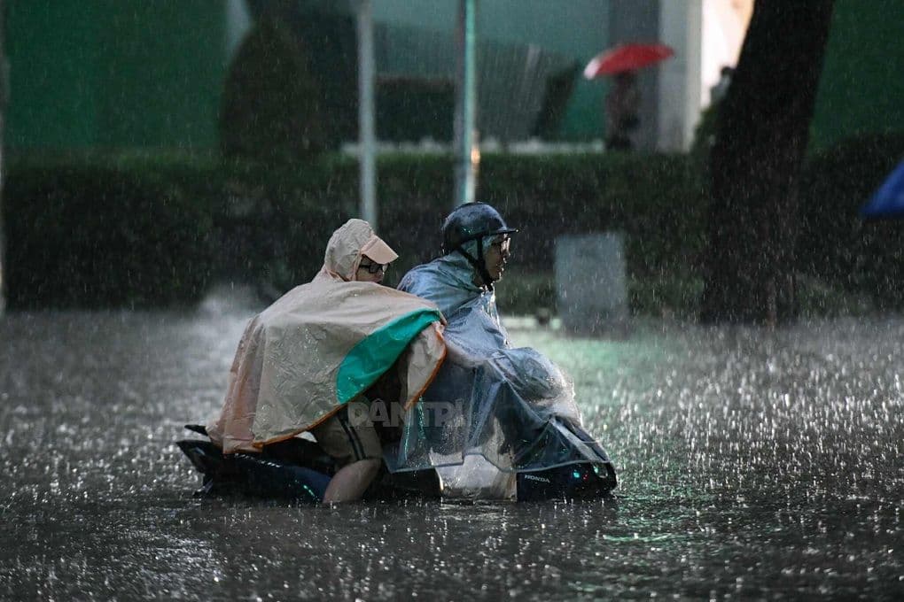 Người dân Hà Nội đi xe máy trong mưa lớn và đường ngập, thể hiện khó khăn giao thông đô thị