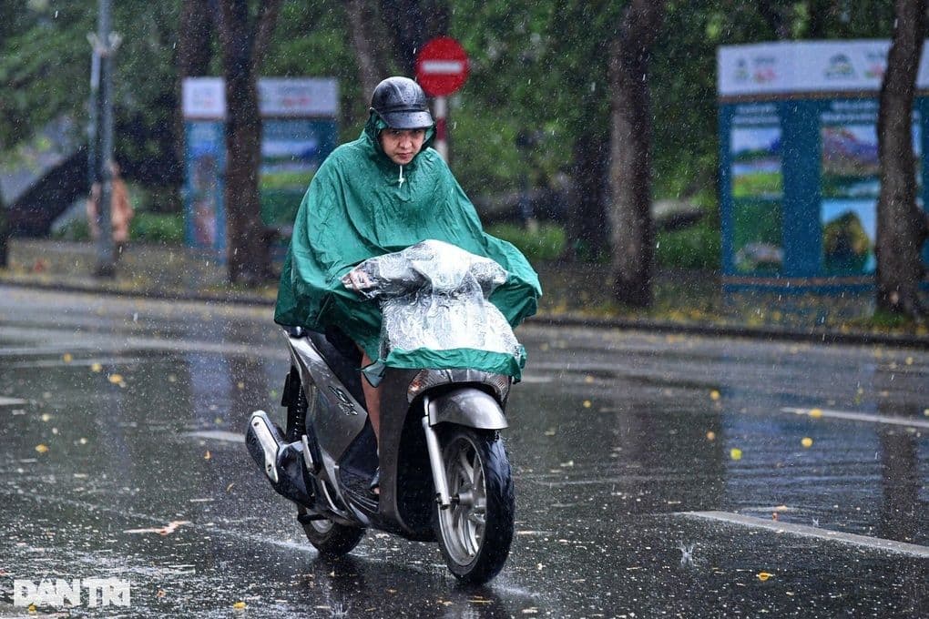 Người dân Hà Nội đi xe máy trong mưa, phản ánh nhịp sống ứng phó với thời tiết