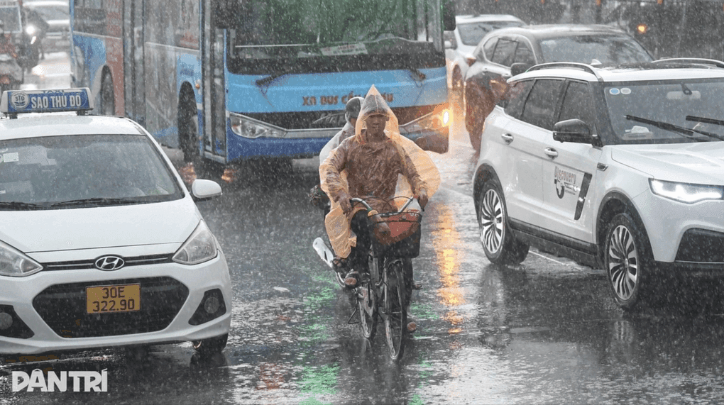 Người dân Hà Nội đi xe đạp trong mưa trên đường phố.