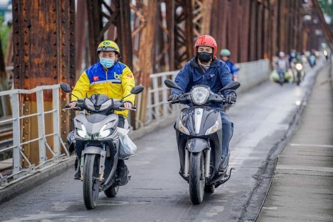 Người dân Hà Nội mặc áo ấm đi xe máy qua cầu Long Biên trong gió lạnh mùa đông.