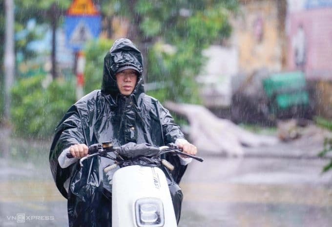 Người dân Hà Nội mặc áo mưa đi xe máy trong cơn mưa chiều