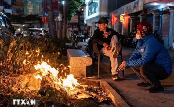 Người dân Hà Nội sưởi ấm bên đống lửa nhỏ trên vỉa hè vào đêm lạnh, minh họa cách giữ ấm hiệu quả