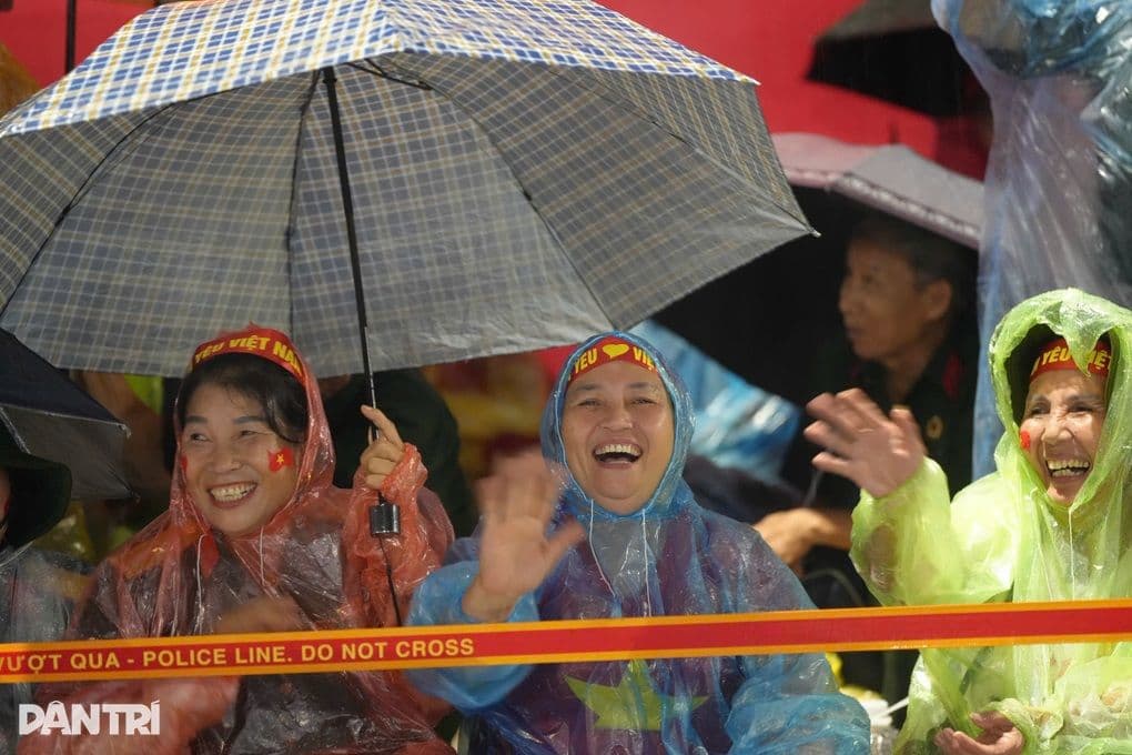 Người dân Huế mặc áo mưa, đội nón lá cười tươi giữa trời mưa bão, thể hiện tinh thần kiên cường và thích nghi.