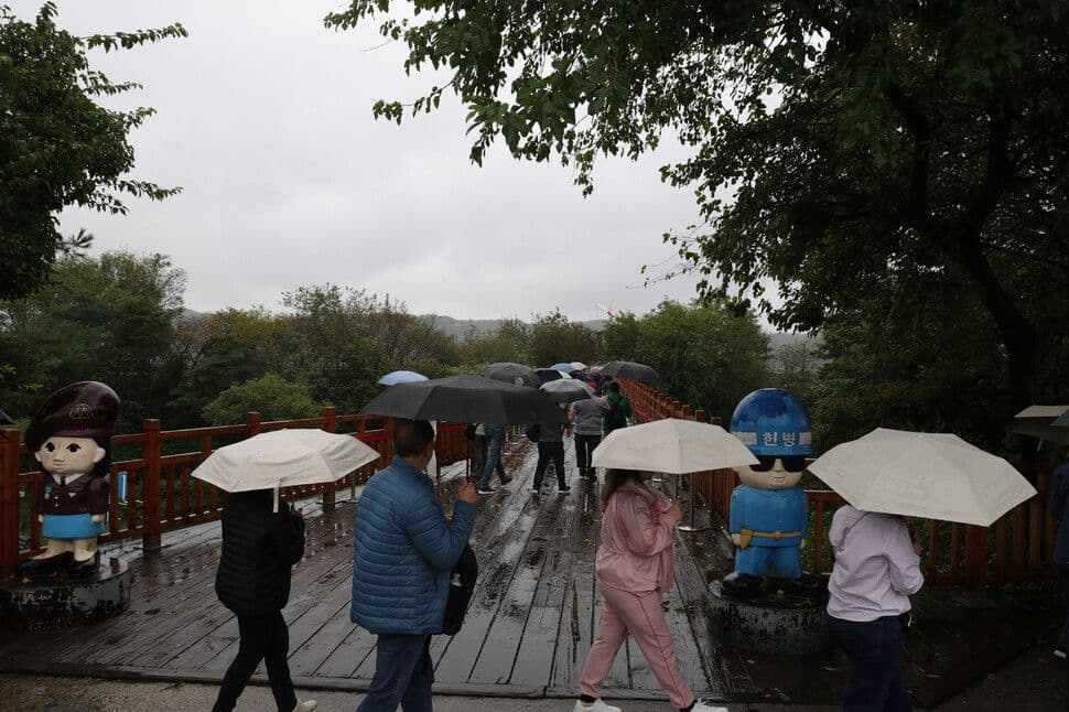 Người dân đi bộ dưới mưa với ô, tượng trưng cho sự thích nghi và chuẩn bị của cộng đồng trước những bất ổn khó lường của thiên nhiên.