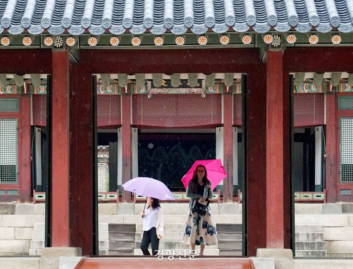 Người dân đi dạo dưới mưa thu với ô, thể hiện sự chuyển mình của thời tiết giao mùa.