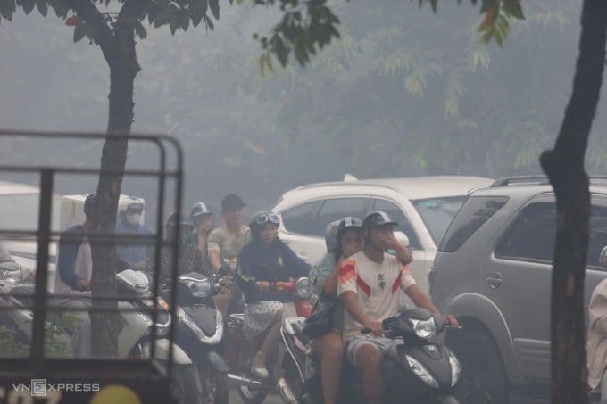 Người dân đi đường bịt mũi do khói đen từ vụ cháy bãi xe dưới chân cầu Vĩnh Tuy.