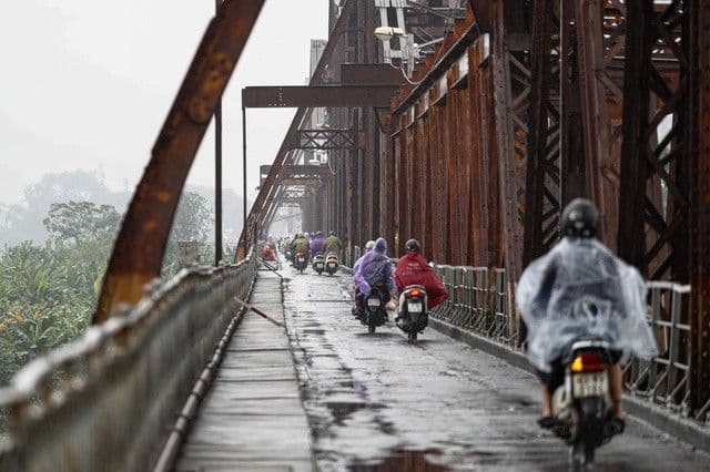 Người dân đi xe máy qua cầu Long Biên trong một ngày mưa phùn, thể hiện hơi lạnh còn sót lại ở miền Bắc.