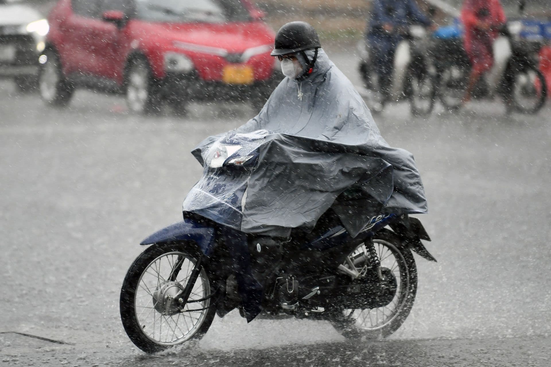 Người dân đi xe máy trong mưa lớn, minh họa việc áp dụng dự báo thời tiết vào các hoạt động hàng ngày.