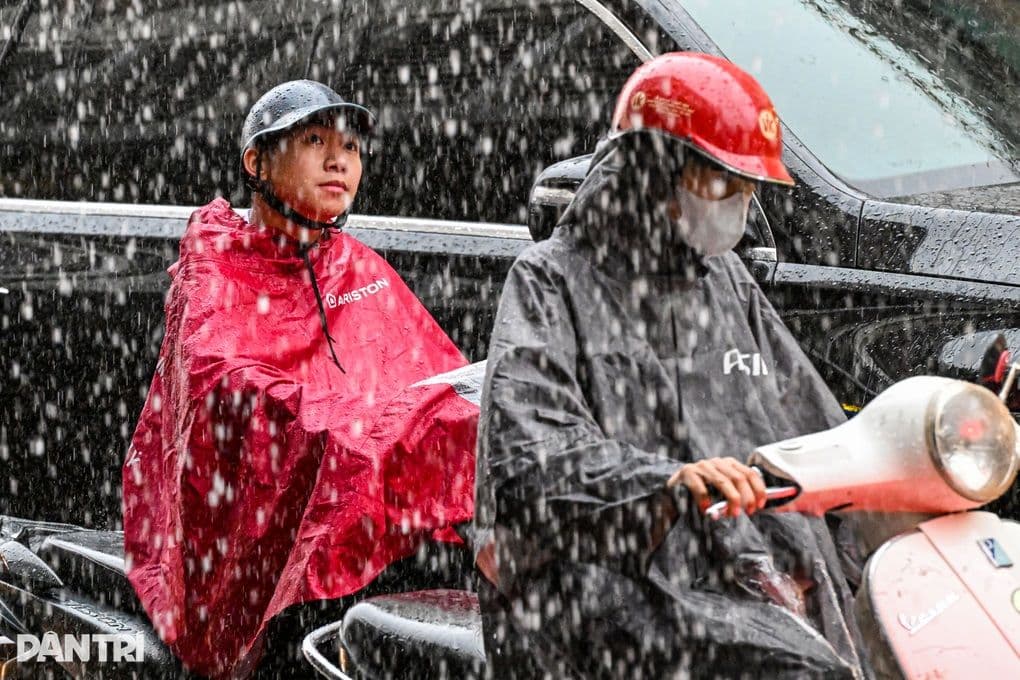 Người dân đi xe máy trong mưa lớn, thể hiện sự khắc nghiệt của thời tiết cực đoan ảnh hưởng đến cuộc sống hàng ngày.