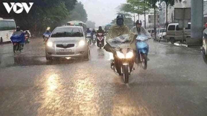 Người dân đi xe máy trong mưa lớn trên đường phố đô thị, minh họa sự gián đoạn giao thông do thời tiết.