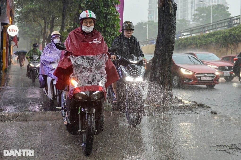 Người dân đi xe máy trong mưa lớn trên đường phố Việt Nam, thể hiện thời tiết mưa dông và sự cần thiết của kế hoạch an toàn.