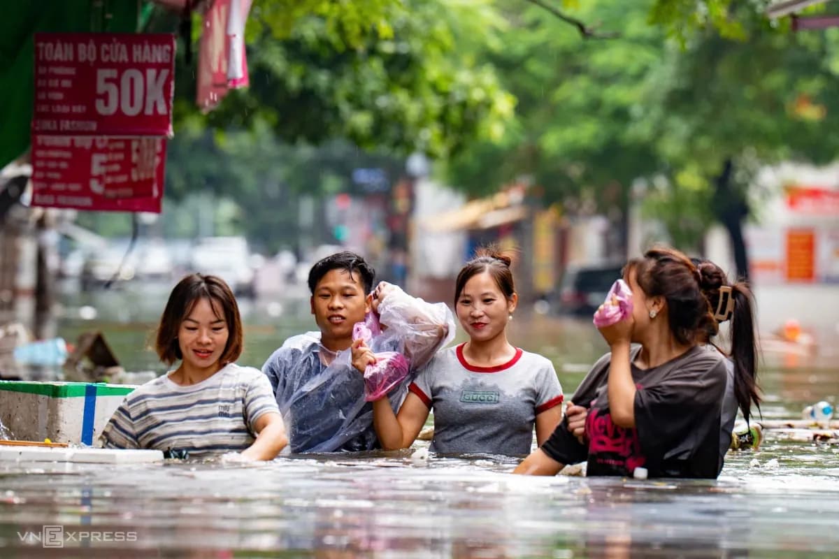 Người dân lội bì bõm trong dòng nước ngập sâu quá bụng trên phố Phan Văn Trường, nhiều phương tiện bị nhấn chìm, minh họa cảnh phố xá biến thành sông sau áp thấp nhiệt đới.