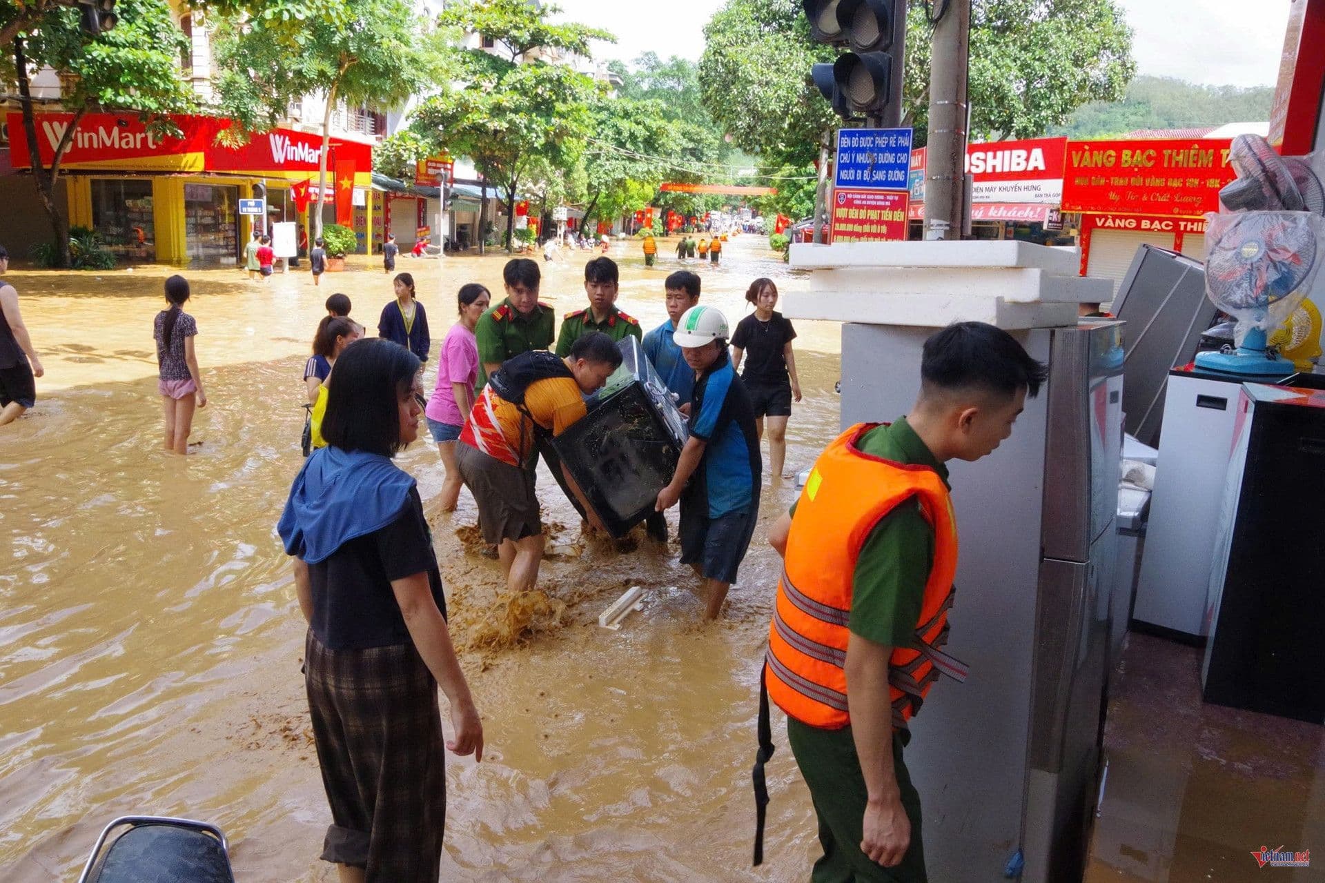 Người dân lội qua dòng nước lũ ngập sâu trên đường phố.