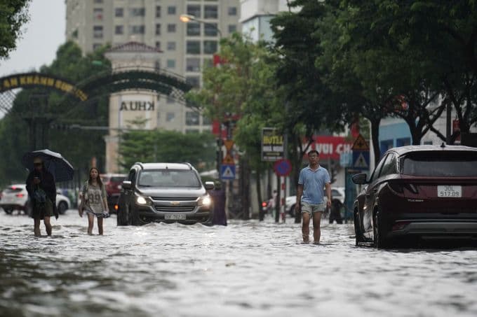 Người dân lội qua đường phố Hà Nội bị ngập sâu do mưa lớn từ bão số 11