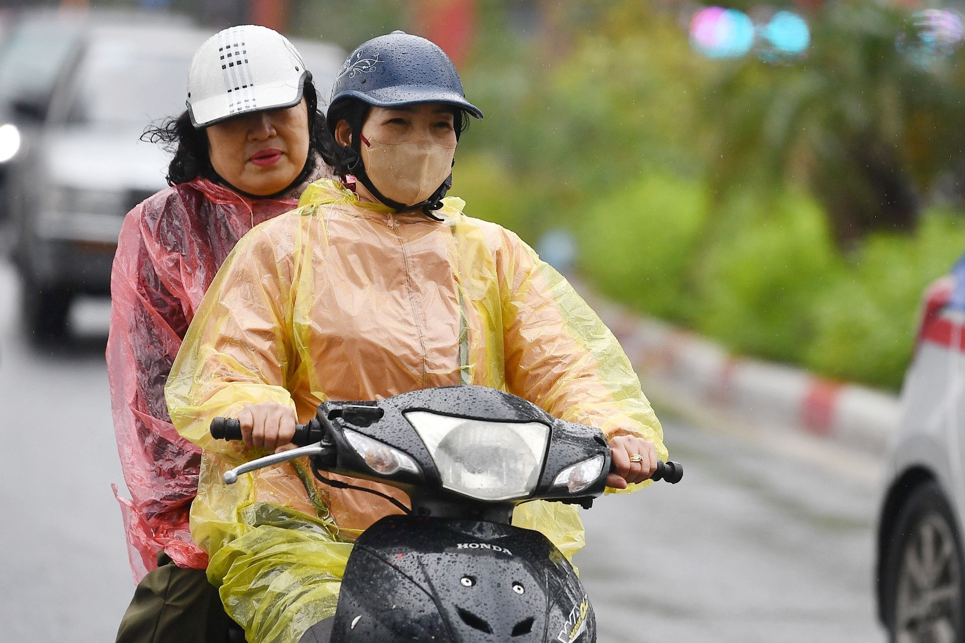 Người dân miền Bắc đi xe máy trong mưa khi không khí lạnh về