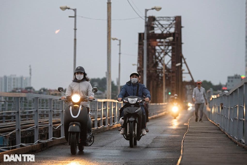 Người dân miền Bắc mặc áo ấm đi xe máy qua cầu, chuẩn bị đón không khí lạnh và mùa đông sớm.
