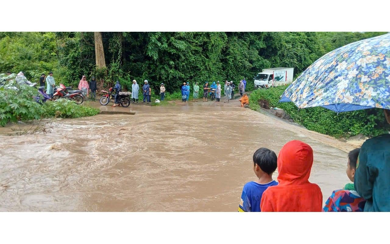Người dân đứng nhìn dòng nước lũ chảy xiết sau bão, thể hiện nguy cơ lũ lụt và sạt lở đất