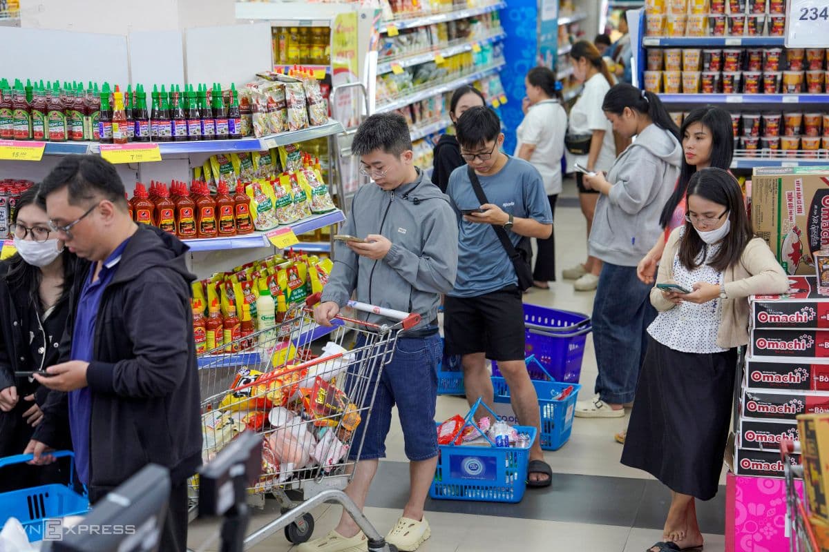 Người dân Đà Nẵng vừa mua sắm vừa theo dõi tin tức bão trên điện thoại, thể hiện sự cảnh giác trước Bão số 12.