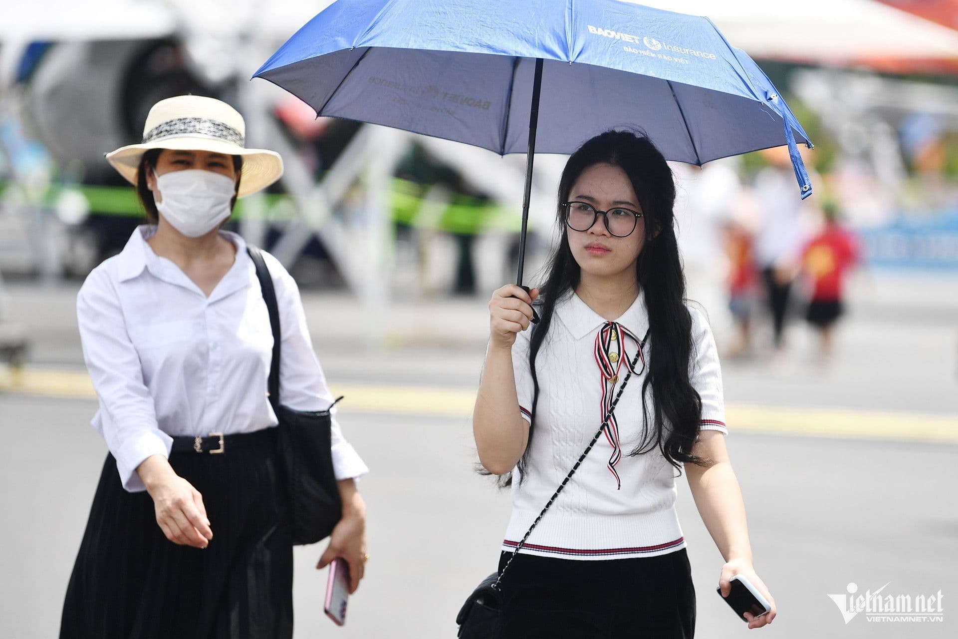 Người dân sử dụng ô và che chắn để thích nghi với thời tiết nắng nóng gay gắt.