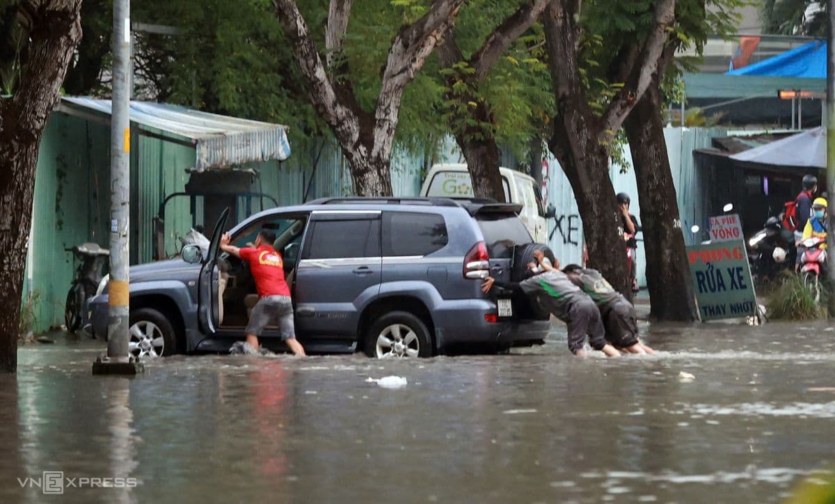 Người dân Sài Gòn bì bõm dắt xe qua đường ngập sâu do triều cường và mưa lớn.