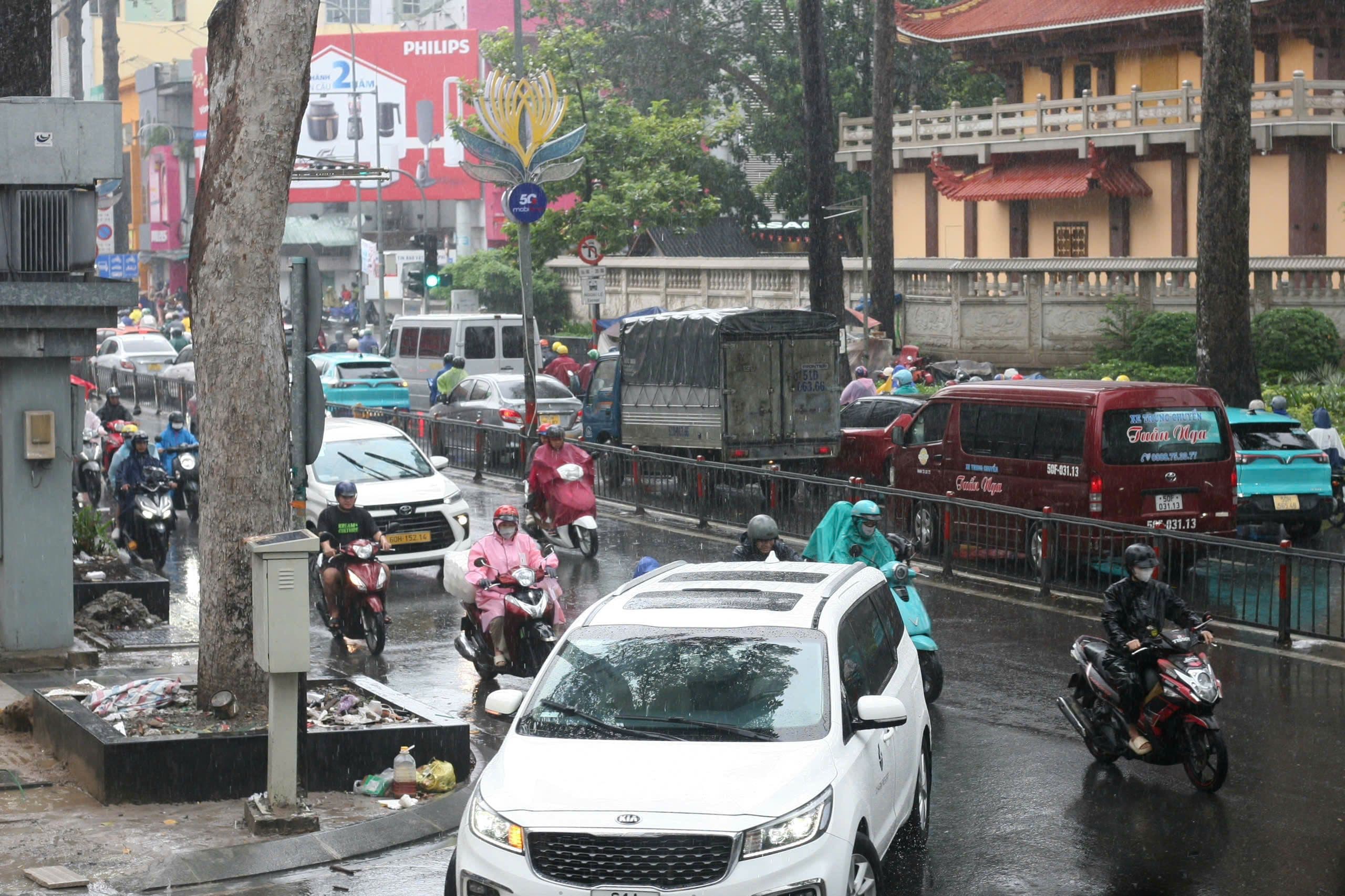 Người dân Sài Gòn chật vật di chuyển qua đường ngập sâu trong mưa lớn.