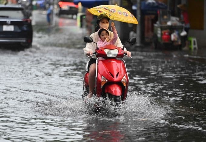 Người dân Sài Gòn lái xe máy qua đường ngập nước sau mưa lớn, phản ánh thách thức đô thị trong mùa mưa.