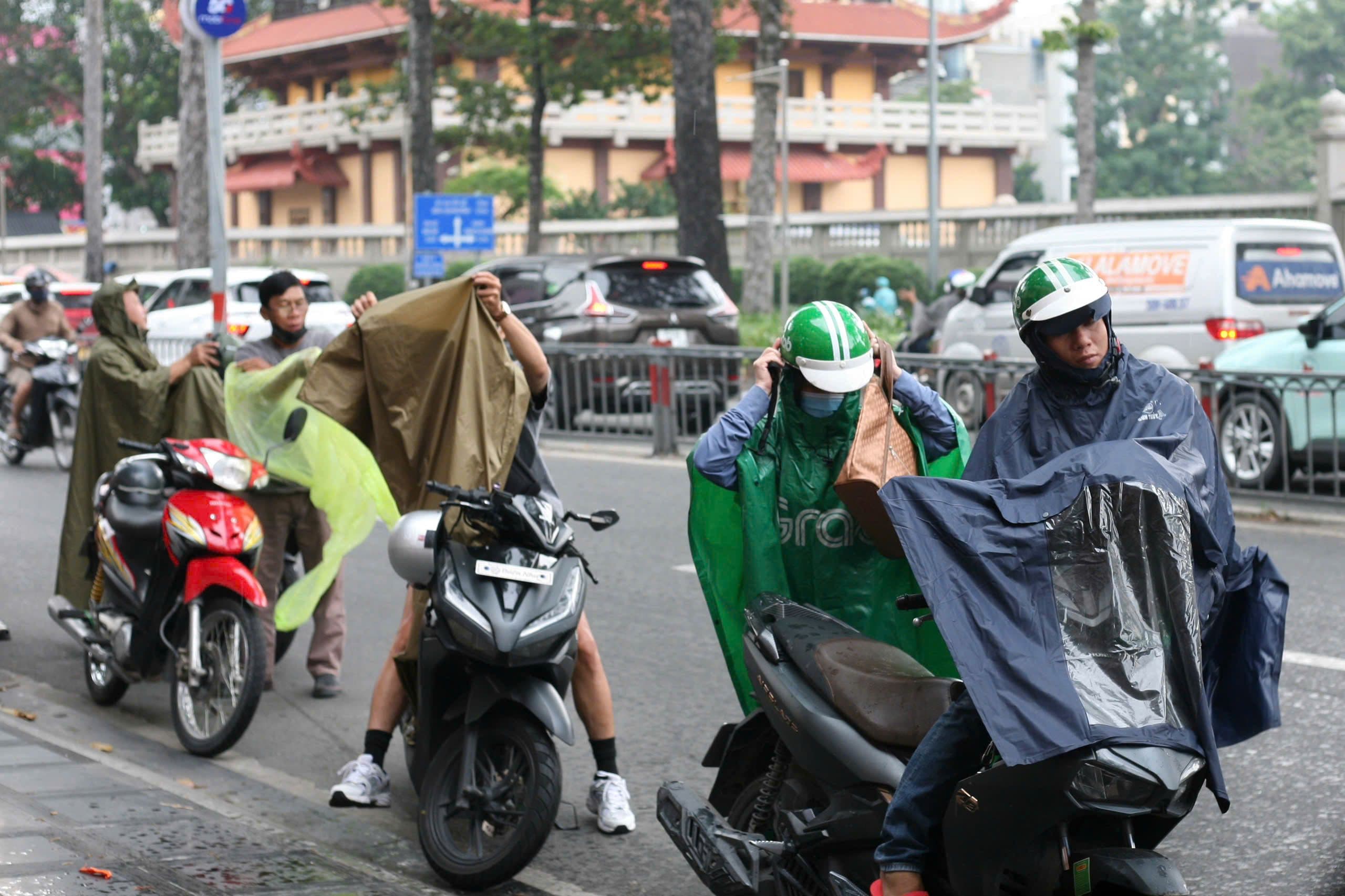 Người dân Sài Gòn mặc áo mưa, chuẩn bị di chuyển trong thời tiết mưa dông.