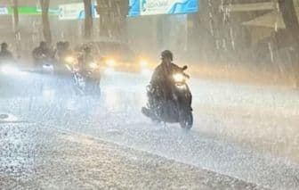 Người dân Sài Gòn mặc áo mưa di chuyển trong cơn mưa lớn, thể hiện sự thích nghi với thời tiết.