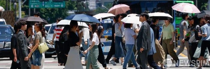Người dân đô thị che ô và đội mũ đi bộ dưới trời nắng gắt, thể hiện tác động của thời tiết lên nhịp sống hàng ngày.