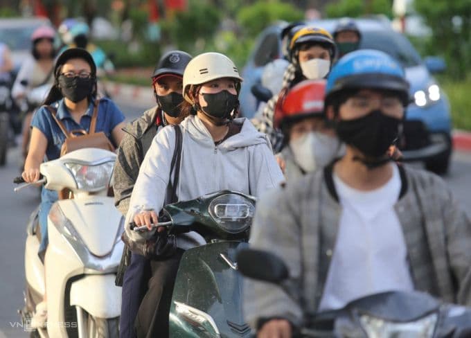 Người dân tham gia giao thông trên đường phố Hà Nội, che chắn cẩn thận dưới trời nắng nóng gay gắt.