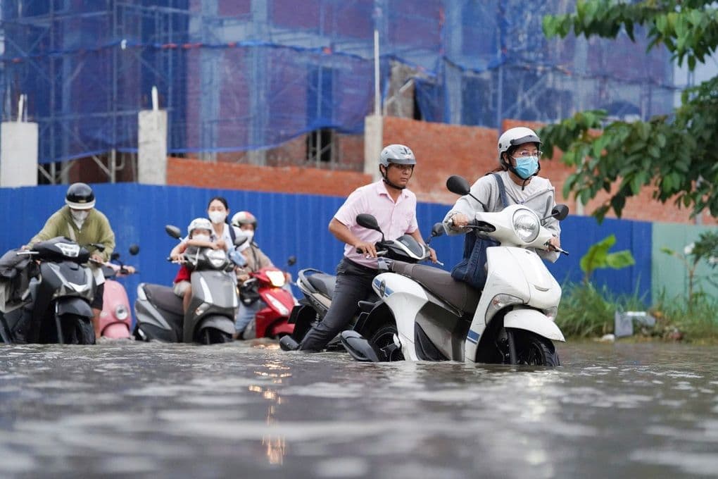 Người dân TP.HCM chật vật di chuyển qua đường ngập sâu do triều cường dâng cao.