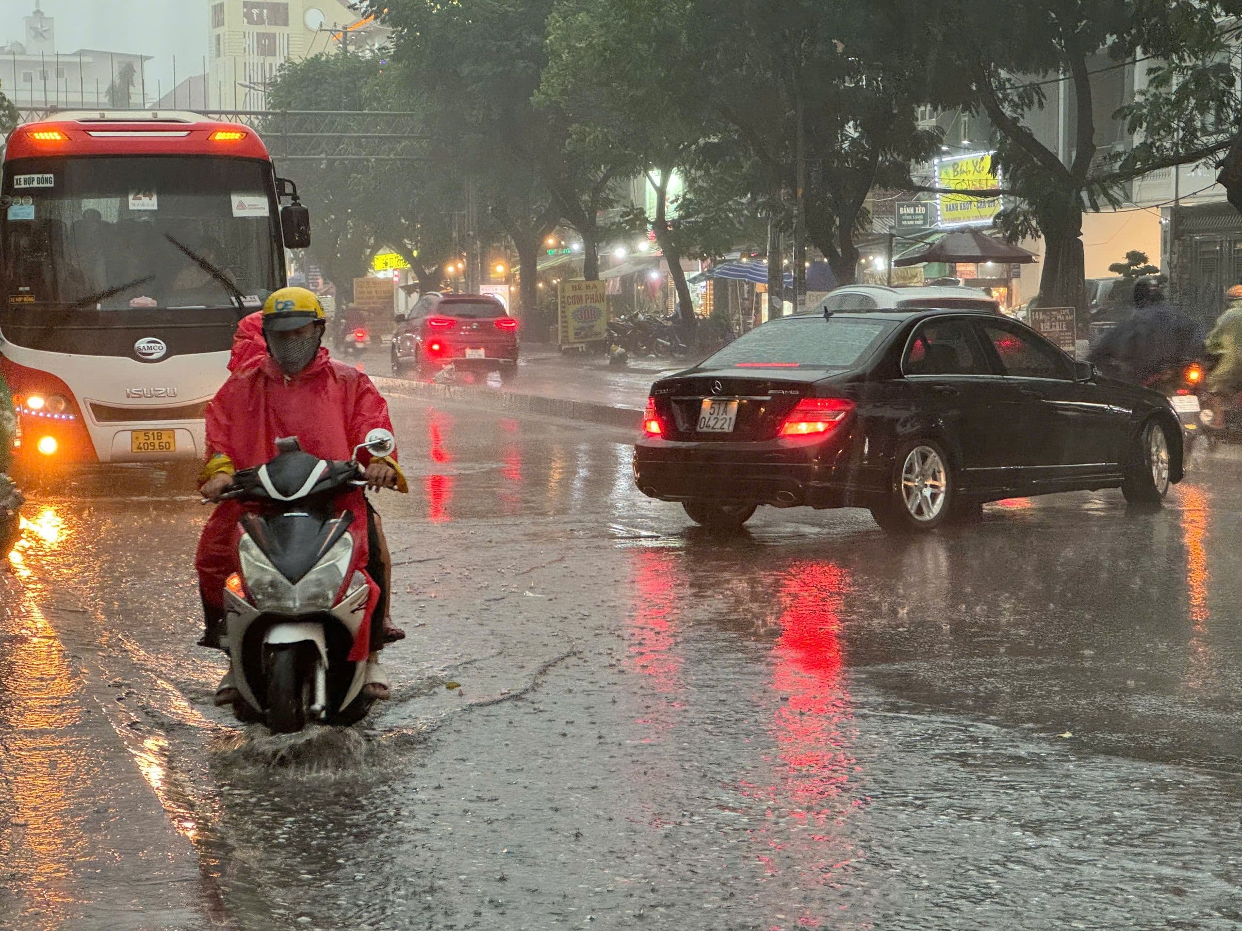 Người dân TP.HCM di chuyển trong cơn mưa chiều, đường phố ướt át, thể hiện sự chuẩn bị cho thời tiết bất ngờ.