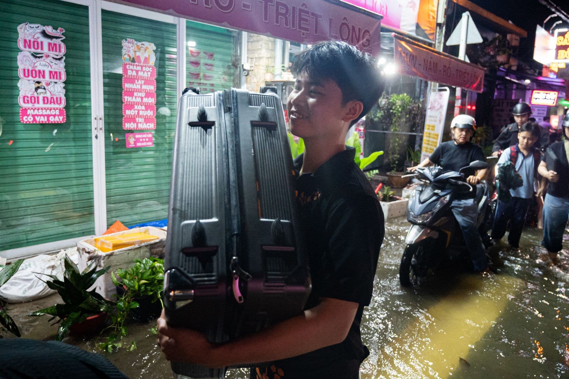 Người dân TP.HCM lội qua đường ngập nước do mưa lớn và triều cường