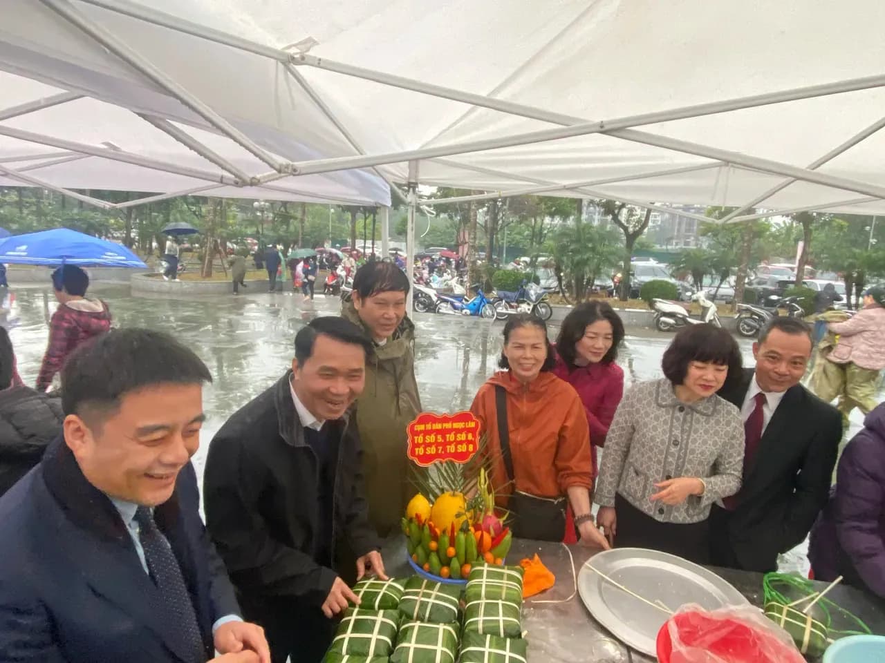 Người dân và cán bộ cùng nhau gói bánh chưng tại phiên chợ Tết, thể hiện tinh thần cộng đồng