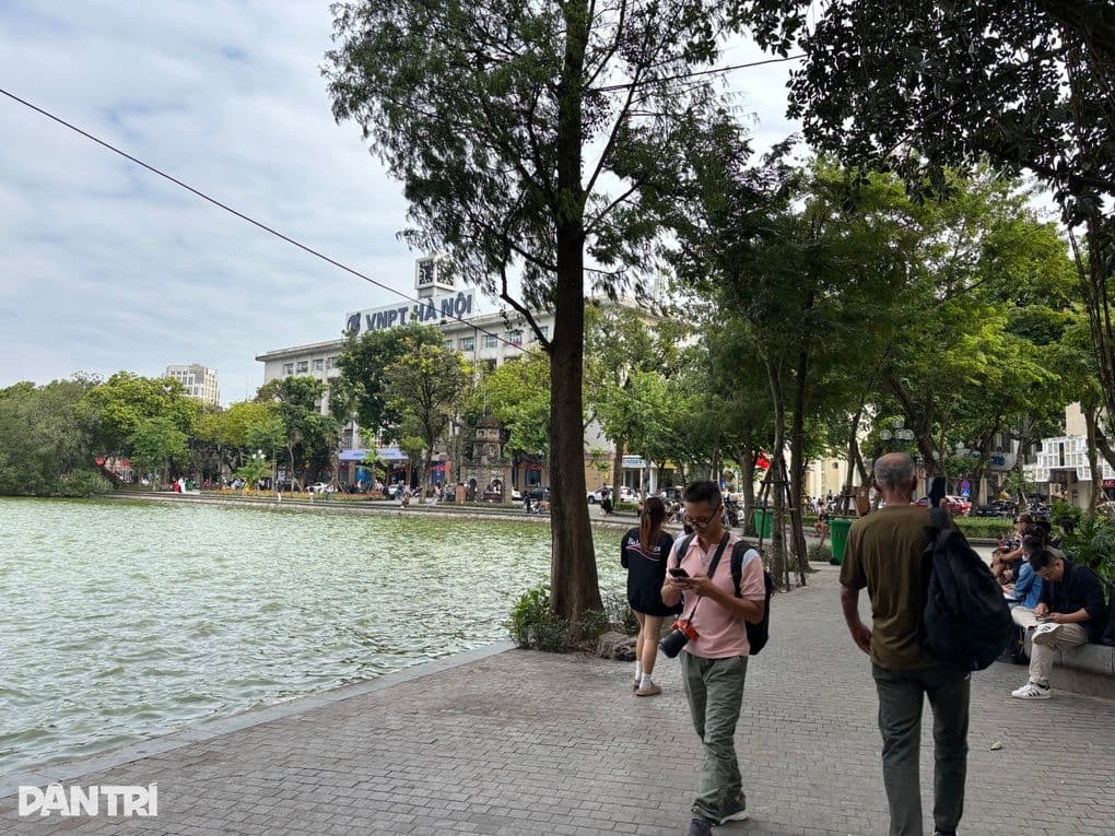 Người dân và du khách đi dạo quanh Hồ Gươm, phản ánh nhịp sống đô thị hối hả.